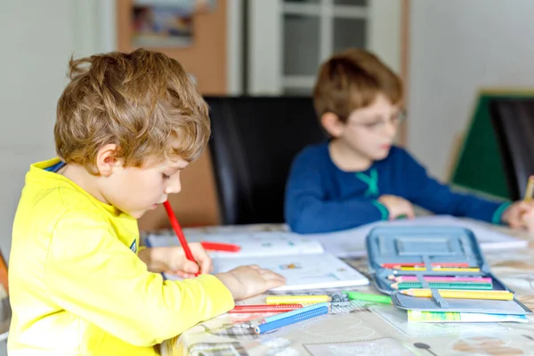Due ragazzi laboriosi della scuola che fanno i compiti durante la quarantena per una pandemia coronarica. Bambini, fratelli che scrivono con la penna, che rimangono a casa. Concetto di istruzione a casa . — Foto Stock