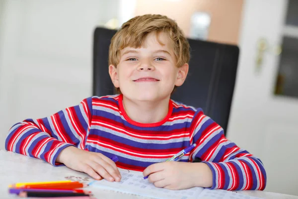 Hårt arbetande glad skolpojke gör läxor under karantänstid från koronapandemisk sjukdom. Friska barn skriva med penna, stanna hemma. Hemskolekoncept — Stockfoto