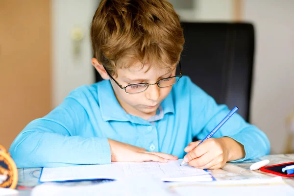Un ragazzo della scuola felice che lavora sodo facendo i compiti durante la quarantena per una pandemia coronarica. Bambino sano che scrive con la penna, rimanendo a casa. Concetto di istruzione a casa — Foto Stock
