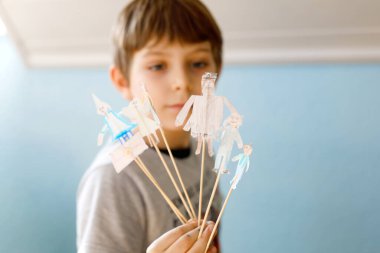 Liseli çocuk kağıt bebek tiyatrosu yapıyor. Mutlu çocuk evde karantina zamanında figürler yaratıyor ve sahne oyunu sergiliyor. Evde kalan yaratıcı çocuk..