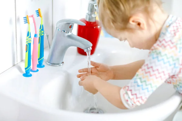 Primer plano de la niña pequeña lavándose las manos con agua y jabón en el baño. Primer plano del niño aprendiendo a limpiar partes del cuerpo. Acción rutinaria de higiene durante la enfermedad viral. niño en casa o guardería. — Foto de Stock