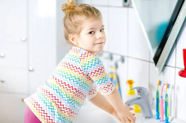 Cute little toddler girl washing hands with soap and water in bathroom. Adorable child learning cleaning body parts. Hygiene routine action during viral desease. kid at home or nursery. — Stock Photo, Image