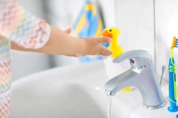 Close-up van kleine peuter meisje wassen handen met zeep en water in de badkamer. Close-up kind leren schoonmaken lichaamsdelen. Hygiëne routine actie tijdens virale desease. kind thuis of in de kinderkamer. — Stockfoto