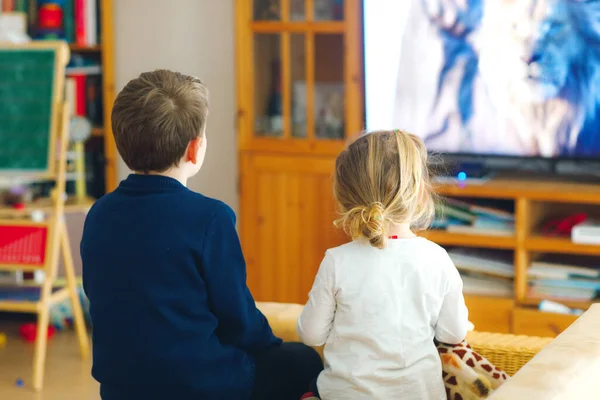 Söt liten småbarnstjej och skolpojke som tittar på djurfilm eller film på tv. Glada friska barn, syskon under coronavirus karantän stanna hemma. Broder och syster tillsammans. Inget ansikte — Stockfoto