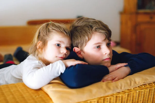 Søt liten barnepike og skolegutt som ser på dyrefilm eller film på tv. Lykkelige, friske barn, søsken under karantenen. Bror og søster sammen. – stockfoto