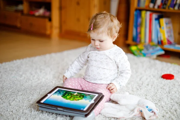 Bonito adorável bebê menina assistindo desenhos animados no tablet pc. Todder criança em casa tocando na tela e jogando jogos educativos no computador . — Fotografia de Stock