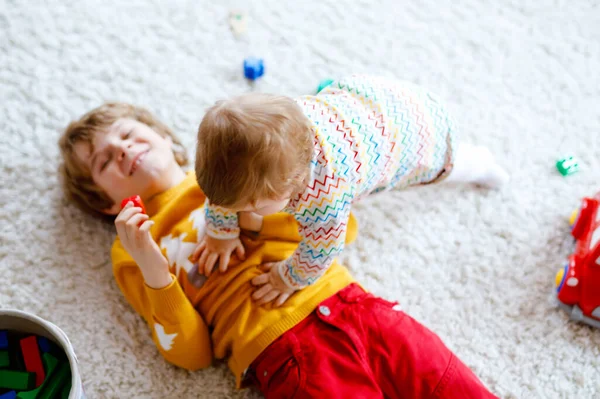 Gelukkig vrolijk baby meisje spelen met verschillende kleurrijke speelgoed thuis. Schattig gezond peuter kind dat plezier heeft met alleen spelen. Actieve vrijetijdsbesteding binnen, in de kinderkamer of op de speelplaats. — Stockfoto