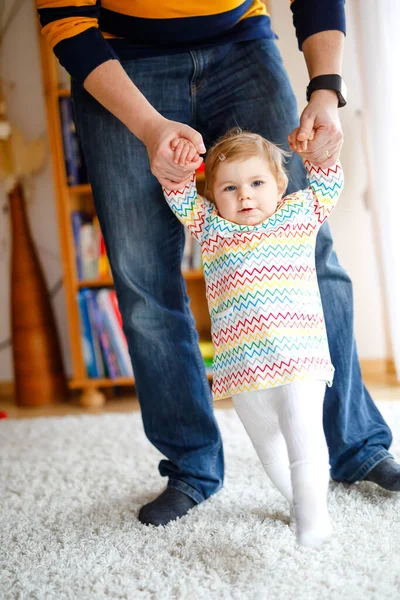 Αξιολάτρευτο κοριτσάκι κάνει τα πρώτα βήματα. Πατέρας διδάσκει την κόρη περπατώντας. Κράτημα με τα χέρια — Φωτογραφία Αρχείου