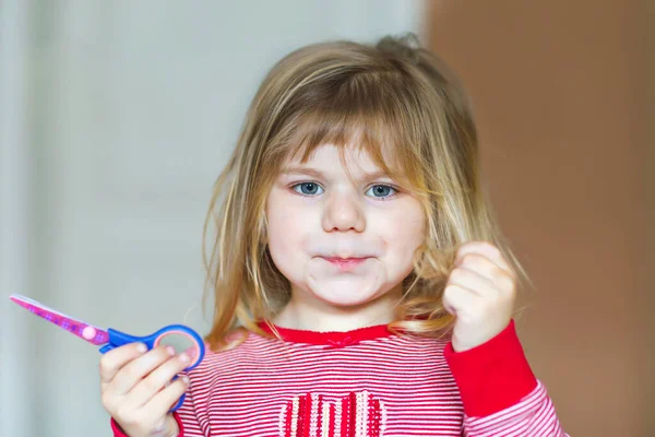 Kleine süße Kleinkind Mädchen machen Experimente mit Scheren und Haare schneiden. Lustiges Baby schneidet ihr Pony zu Hause selbst. Ärger — Stockfoto