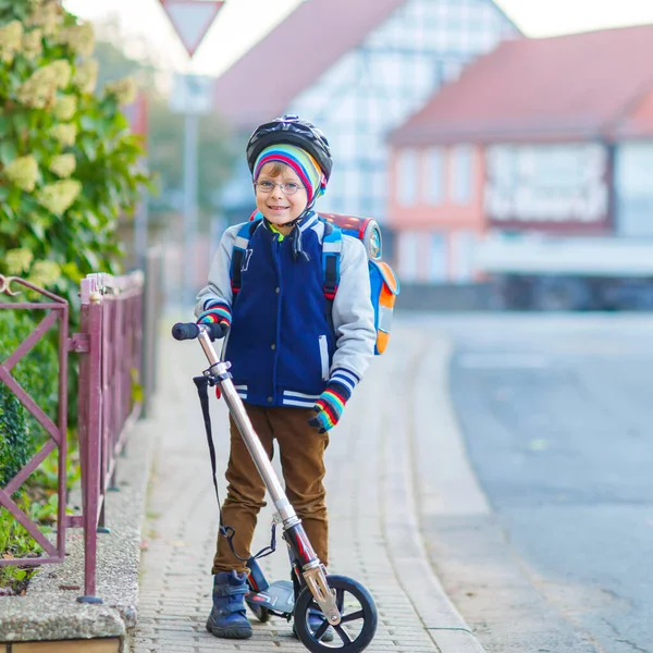 Kasklı küçük çocuk şehirde scooterıyla geziyor. — Stok fotoğraf