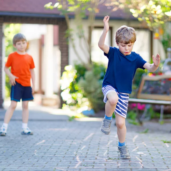 Twee kleine school en kleuters spelen hopscotch op de speelplaats — Stockfoto