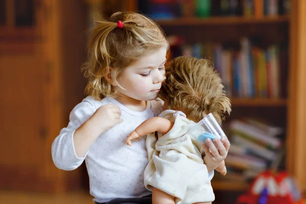 Adorable cute little toddler girl playing with doll. Happy healthy baby child having fun with role game, playing mother at home or nursery. Active daughter with toy — Stock Photo, Image