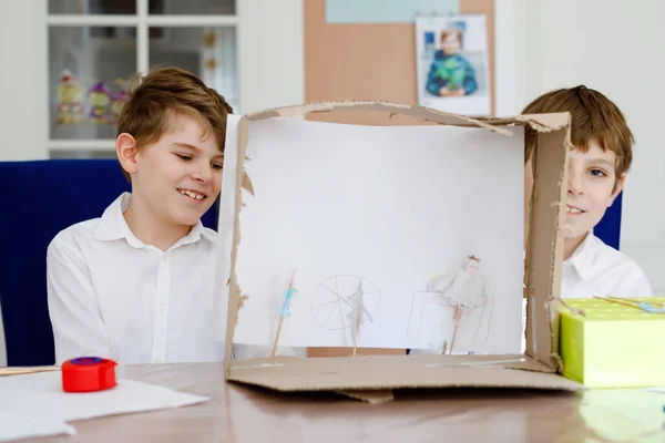 Dos niños de escuela haciendo teatro de muñecas de papel. Niños felices y amigos creando figuras y representando obras de teatro durante el tiempo de cuarentena en casa. Hermanos creativos activos que se quedan en casa . —  Fotos de Stock