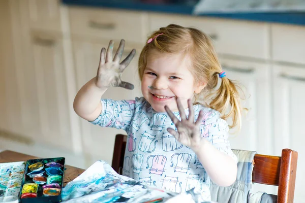 Sulu boyayla resim yapmayı öğrenen sevimli bir bebek. Evde renkli fırçalar kullanarak resim yapan küçük bir çocuk. Kirli yüzü ve elleri evde ya da çocuk odasında olan sağlıklı mutlu bir çocuk. — Stok fotoğraf