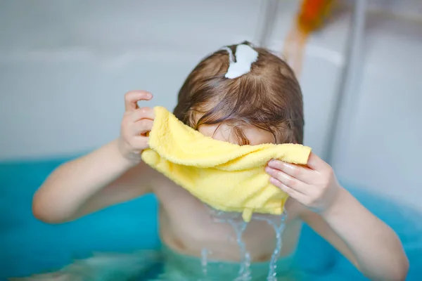 Niedliches kleines Kind, das mit Wasser spielt, indem es zu Hause in der Badewanne badet. Entzückend glücklich gesunden Vorschulkind Jungen Spaß haben, Haare und Kopf waschen und mit Seife spritzen — Stockfoto