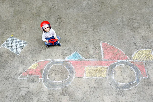 Buon bambino sano divertirsi con disegno immagine cura della razza con gesso. Tempo libero creativo per bambini. Bambino adorabile seduto su asfalto e creando con gessetti colorati . — Foto Stock