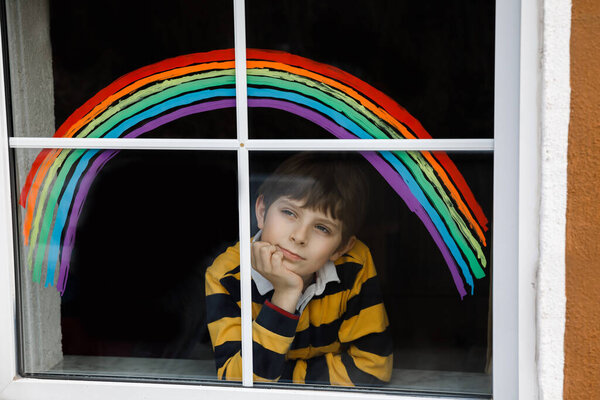 Прекрасный школьник с радугой, раскрашенный красочным окном во время пандемического карантина коронавируса. Детская картина радуги по всему миру со словами Давайте все будет хорошо
.