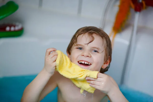 Χαριτωμένο μικρό παιδί παίζει με το νερό κάνοντας μπάνιο στην μπανιέρα στο σπίτι. Αξιολάτρευτο ευτυχισμένο παιδί προσχολικής ηλικίας που διασκεδάζει, πλένει τρίχες και το κεφάλι και πιτσιλάει με σαπούνι — Φωτογραφία Αρχείου