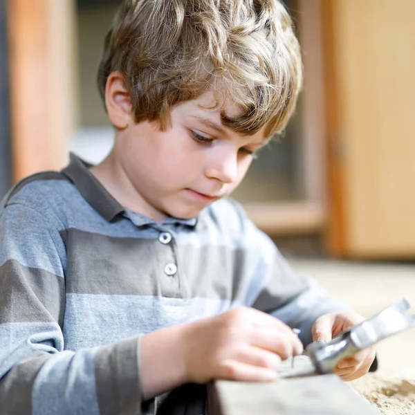 Glücklicher kleiner Junge, der mit Spielzeug auf der Baustelle hilft. Lustiges Kind von 7 Jahren, das Spaß am Bau eines neuen Familienhauses hat. Kind mit Nägeln und Hammer hilft Vater bei Renovierung von altem Haus. — Stockfoto