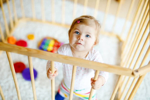 Hermosa niña pequeña de pie dentro del parque infantil. Lindo niño adorable jugando con juguetes coloridos. Hogar o guardería, seguridad para los niños. Bebé solo esperando a mamá — Foto de Stock