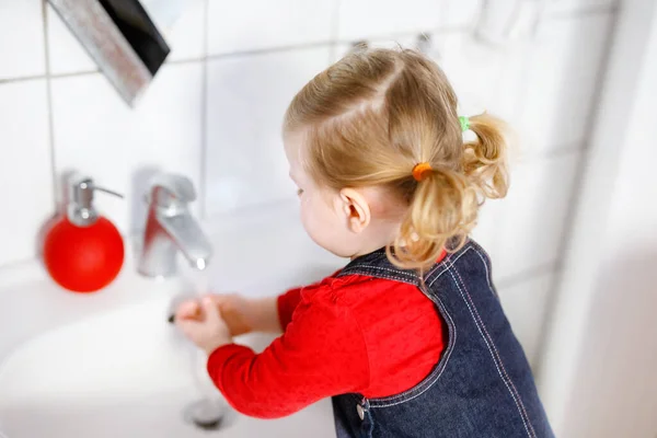 Schattig klein peuter meisje wassen handen met zeep en water in de badkamer. Schattig kind leren schoonmaken lichaamsdelen. Ochtendhygiëne. Gelukkig gezond kind thuis of in de kinderkamer. — Stockfoto