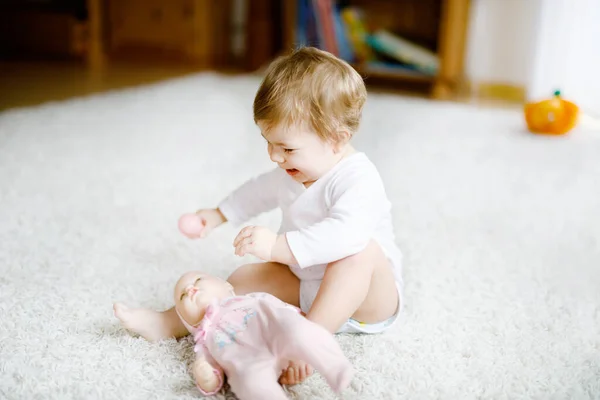 Preciosa linda y hermosa niña jugando con muñequita de juguete en casa o guardería. Feliz niño sano divirtiéndose con diferentes juguetes. Niños pequeños aprendiendo diferentes habilidades. —  Fotos de Stock