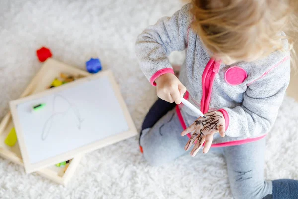 Primo piano della bambina che impara a dipingere con pennarelli. Bambino piccolo disegno su mani e vestiti . — Foto Stock