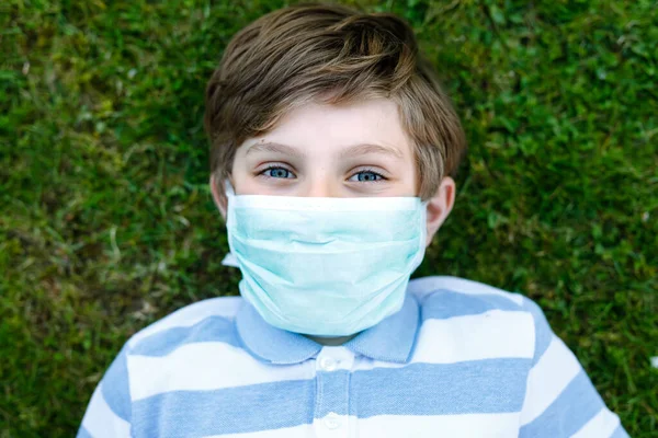 Чарівний хлопчик у медичній масці як захист від пандемії коронавірусної хвороби. Шкільна дитина використовує захисне обладнання як боротьбу з ковадлом 19 . — стокове фото