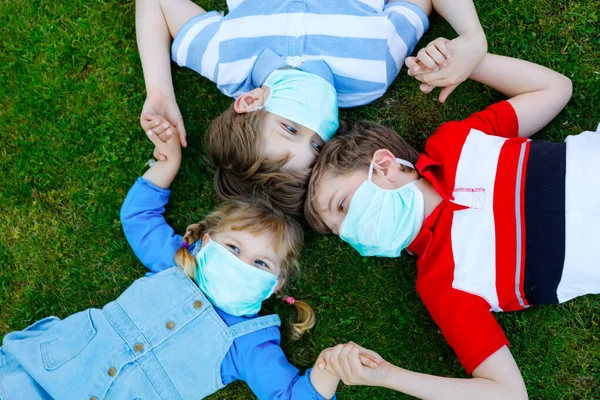 Троє дітей, маленька дівчинка-малюк і двоє хлопчиків у медичній масці як захист від пандемії коронавірусної хвороби. Діти, милі брати і сестри використовують захисне обладнання як боротьбу проти ковадла 19 . — стокове фото
