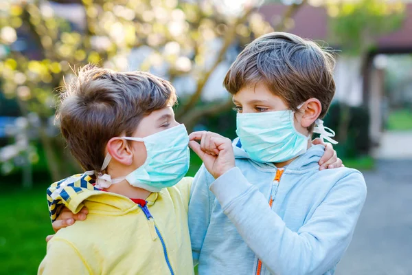 Dois miúdos com máscara médica como protecção contra a doença do coronavírus pandémico. Crianças, irmãos encantadores e melhores amigos usando equipamentos de proteção como luta contra o covid 19. — Fotografia de Stock