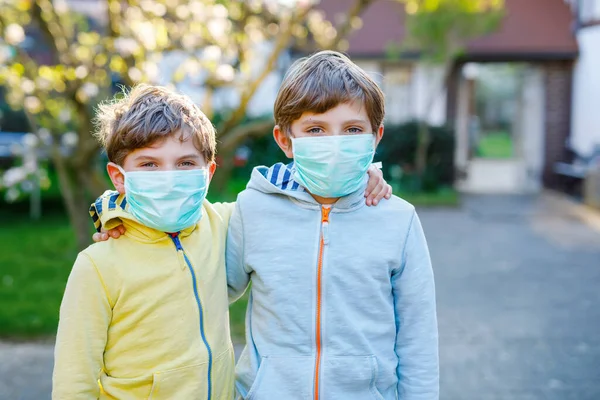 Due ragazzi mascherati come protezione contro la pandemia coronavirica. Bambini, fratelli e sorelle adorabili e migliori amici che usano attrezzature protettive come lotta contro covid 19. — Foto Stock