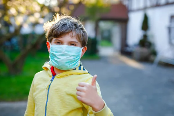 Adorable niño con máscara médica como protección contra la enfermedad de cuarentena por coronavirus pandémico. Niño en edad escolar usando equipo de protección como lucha contra el covidio 19 . — Foto de Stock