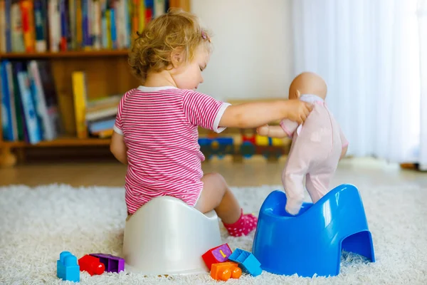 Gros plan de mignon petit enfant de 12 mois bébé fille assis sur pot. Enfant jouant avec un jouet de poupée. Concept de formation aux toilettes. Apprentissage des bébés, étapes de développement — Photo