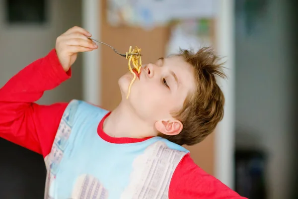 Leuke gezonde kleuter jongen eet pasta noedels zittend op school of kinderdagverblijf cafe. Gelukkig kind dat gezond biologisch en veganistisch voedsel eet in restaurant of thuis. Jeugd, gezondheidsconcept — Stockfoto