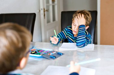 Corona ve Covin 19 salgın hastalığından karantina zamanında ödev yapan iki çalışkan okul çocuğu. Çocuklar, kardeşlerim kalemle yazıyor, evde kalıyorlar. Evde eğitim kavramı.