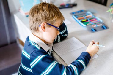 Çalışkan, mutlu okul çocuğu Corona salgınından dolayı karantina zamanında ödev yapıyor. Kalemle yazan sağlıklı bir çocuk, evde kalıyor. Evde eğitim kavramı