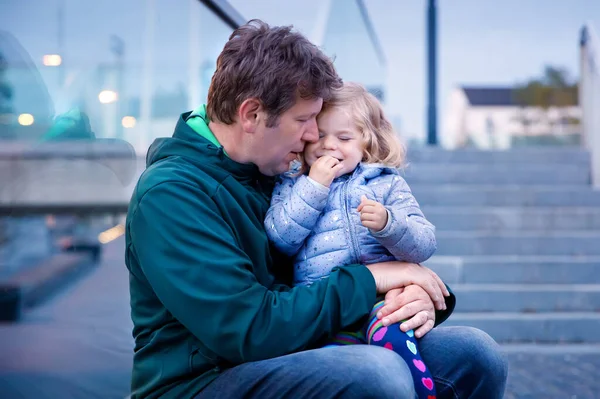 Beautiful portrait of cute little toddler girl with father. Happy baby child hugging with dad. Lovely family of man and daughter. Outdoors at the dusk. — Stock Photo, Image