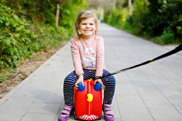 Kleines Kleinkind, das in einem Park mit pandemischer Coronavirus-Krankheit spazieren geht. Niedliche entzückende Kind spielt mit Spielzeugauto Koffer auf Rädern — Stockfoto