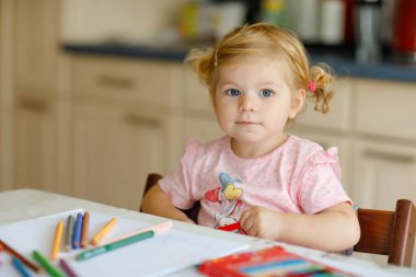 Kalemle resim yapmayı öğrenen sevimli bir bebek. Küçük çocuk renkli keçeli kalemlerle evde resim çiziyor. Evde ya da çocuk odasında renkler deneyen sağlıklı, mutlu bir kız..