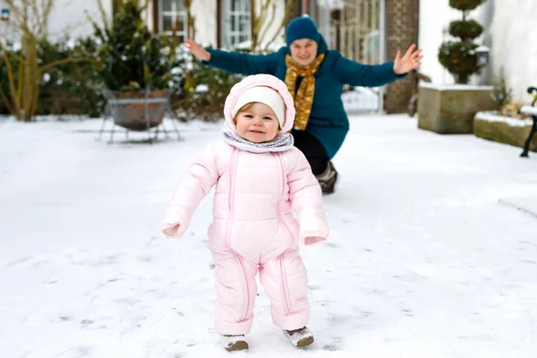 Söt liten flicka gör första steg utomhus på vintern med mamma. Söta småbarn lära sig gå. — Stockfoto