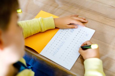 Karantina sırasında Corona salgınından matematik ödevi yapan okul çocuğu. Çocuk çarpım tablosu ve temel matematik kurallarını kalemle yazıp evde kalarak öğreniyor. Evde eğitim kavramı