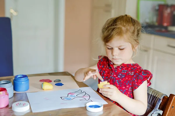 Little toddler girl painting with finger colors and potato stamp during pandemic coronavirus quarantine disease. Happy creative child, homeschooling with parents — Stock Photo, Image