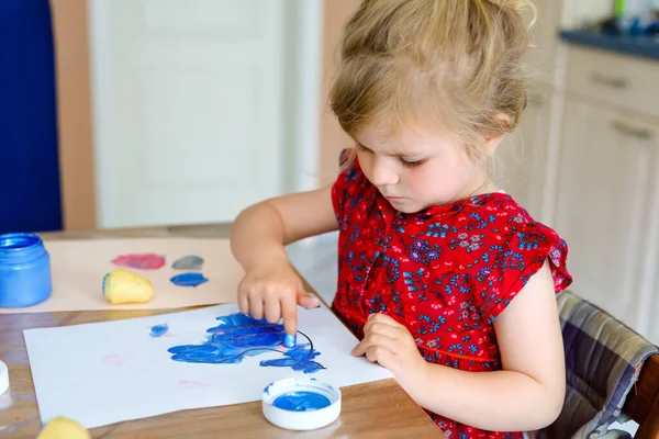 Little toddler girl painting with finger colors and potato stamp during pandemic coronavirus quarantine disease. Happy creative child, homeschooling with parents — Stock Photo, Image