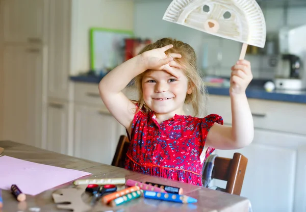 Piccolo bambino ragazza pittura con i colori delle dita rendendo maschera orso animale durante la malattia pandemica coronavirus quarantena. Felice bambino creativo, scuola a casa con i genitori — Foto Stock