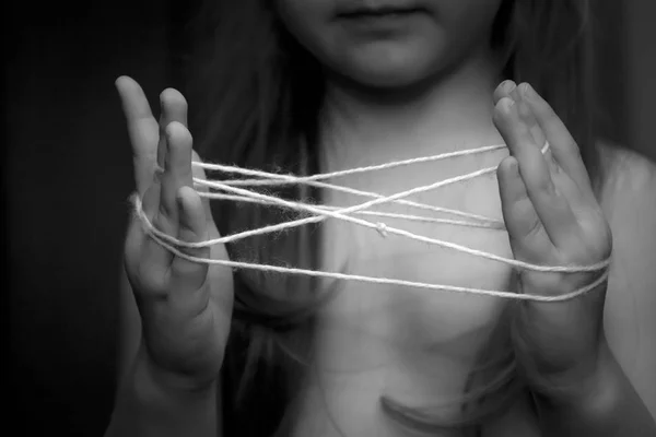 Маленька дівчинка грає з ниткою в руках — стокове фото