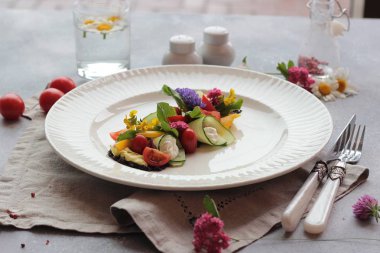 Yaz çiçekler ışık gri arka plan üzerinde beyaz bir plaka üzerinde renkli sebze salatası