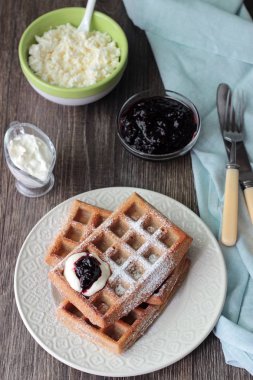 Pudra şekeri ve ahşap masa üzerinde krema ile geleneksel Belçika waffle. Gurme kahvaltı. 