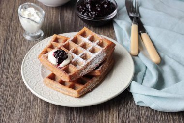 Pudra şekeri ve ahşap masa üzerinde krema ile geleneksel Belçika waffle. Gurme kahvaltı. 