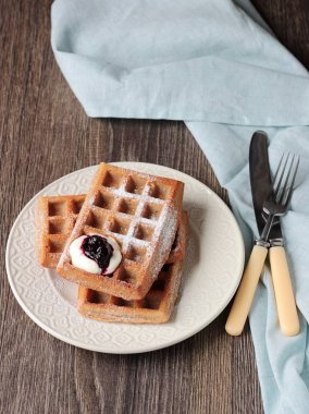 Pudra şekeri ve ahşap masa üzerinde krema ile geleneksel Belçika waffle. Gurme kahvaltı. 