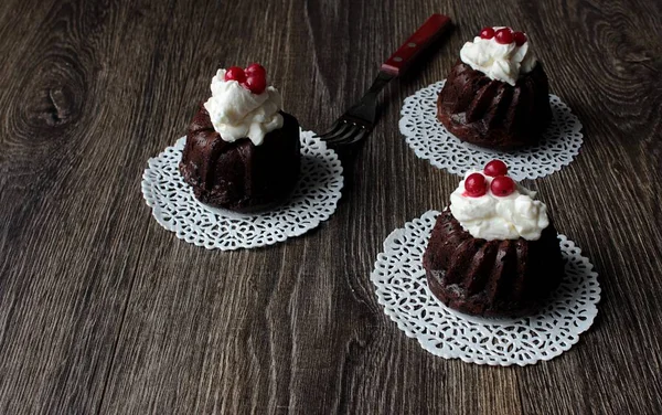 Тёмные шоколадные кексы с ягодами и сливками на тёмном деревянном фоне — стоковое фото
